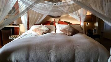 Una cama con dosel, dos almohadas y una mesita de noche con lámpara.