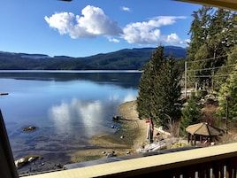 Vista de un lago con un muelle, un pabellón y una zona boscosa.