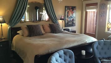 A bedroom with a large bed, a chandelier, a mirror, and a poster on the wall.