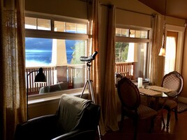 Una habitación con vistas al océano, una mesa de comedor, sillas y una lámpara.