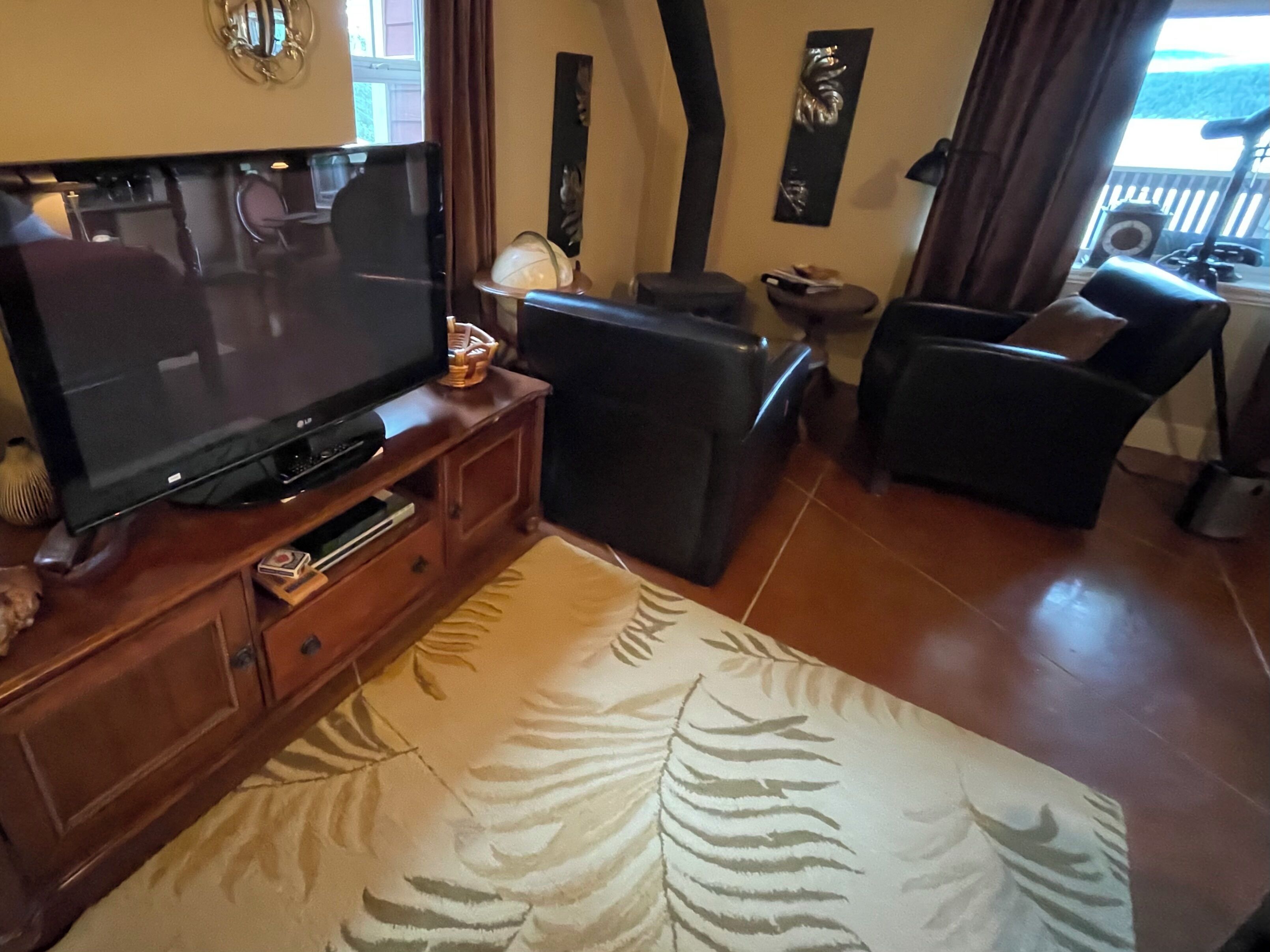 Una sala de estar con televisor de pantalla plana, un sofá, una mesa de centro y un tapete estampado.