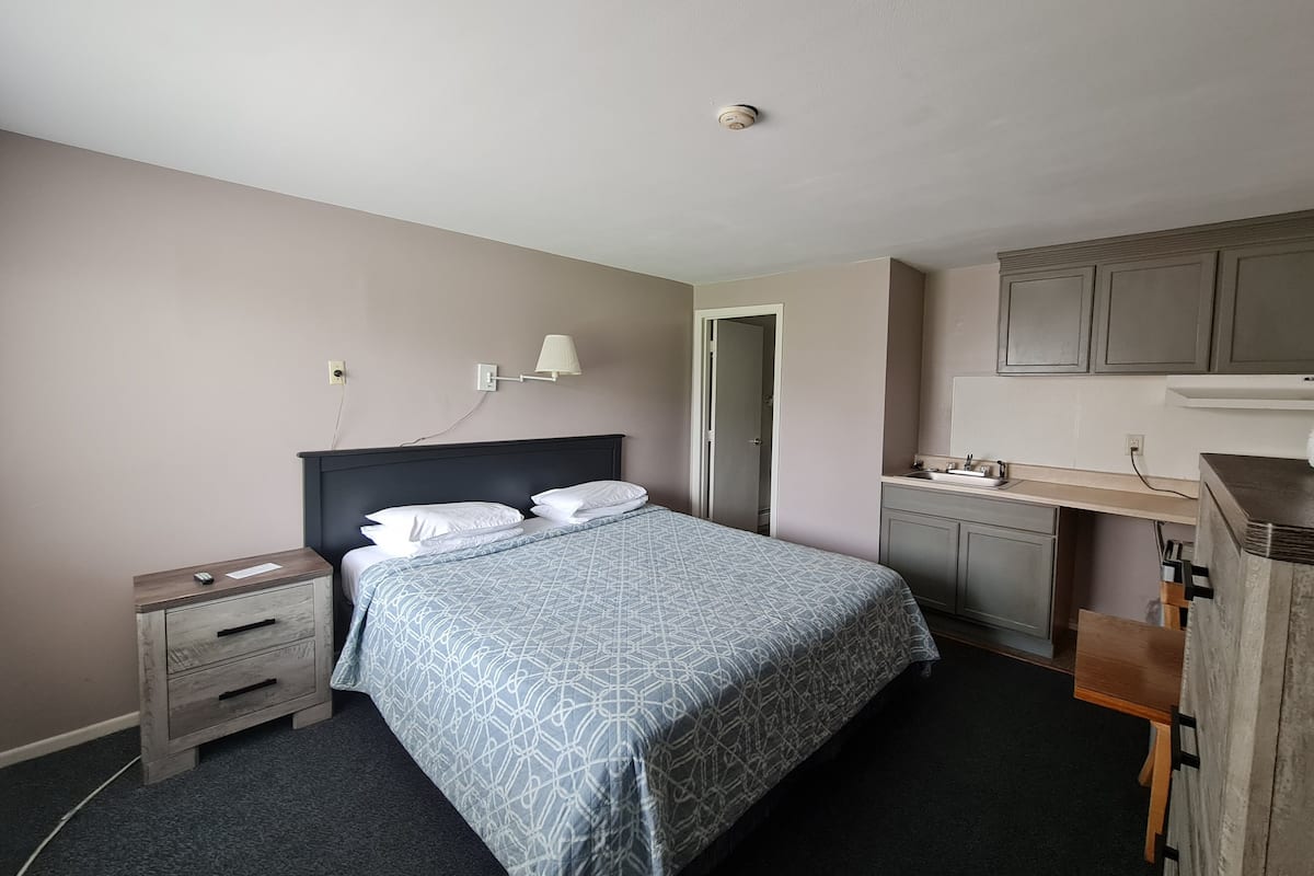 A bedroom with a bed, bedside tables, a desk, and a mirror.