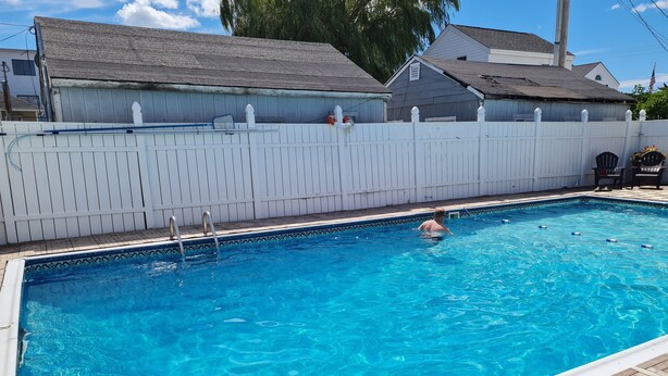 A rectangular swimming pool with a wooden deck surrounding it. - Flagship Motor Court (Hampton)