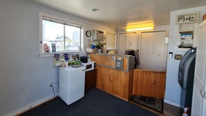 A compact kitchen with a refrigerator, microwave, and sink. There is a window with a view of buildings outside. - Flagship Motor Court (Hampton)