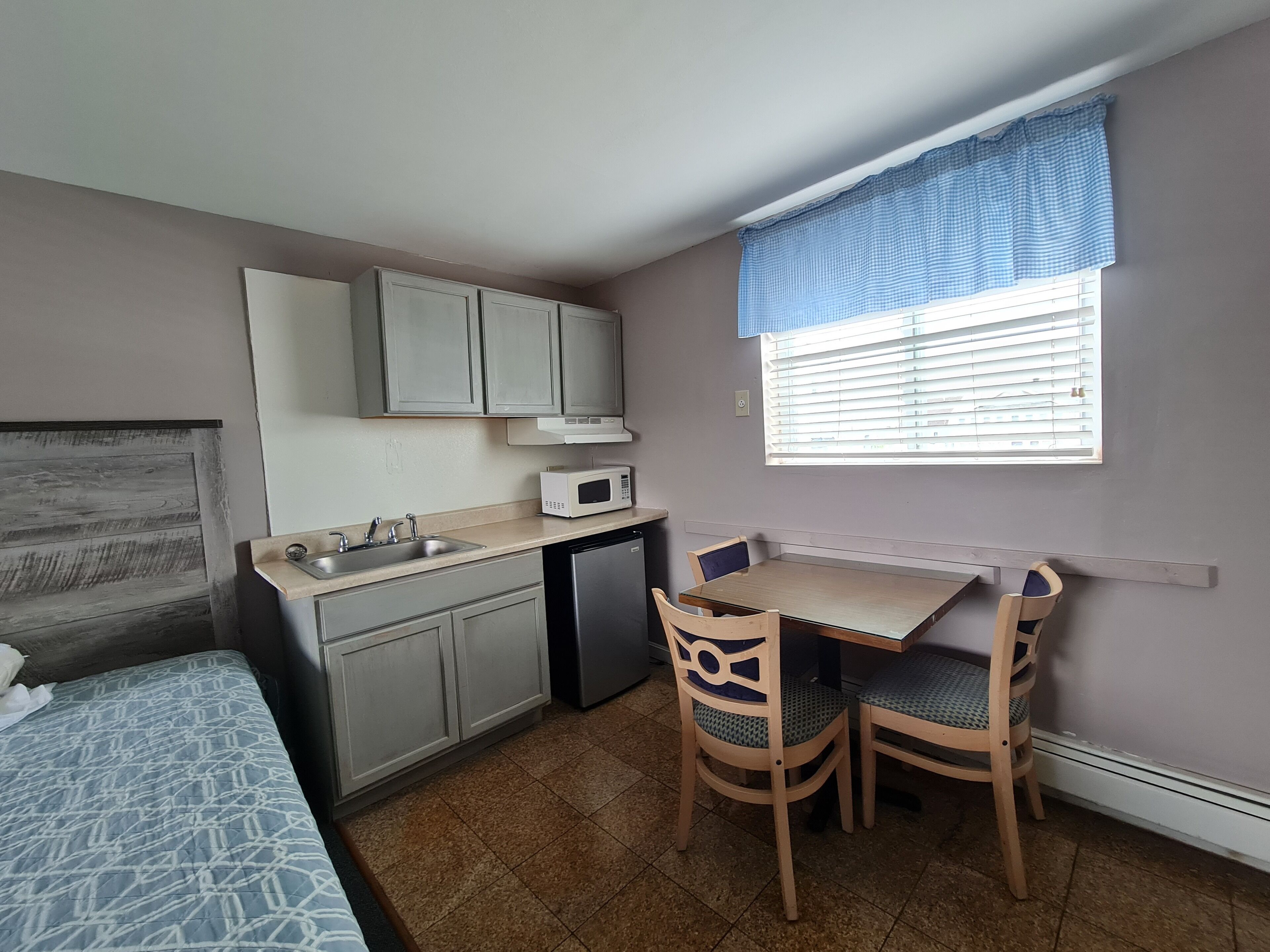 A compact kitchen with a sink, microwave, and a small dining table with chairs.