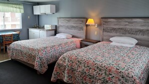 A hotel room with two beds, a small desk, a microwave, and a window with blinds. - Flagship Motor Court (Hampton)