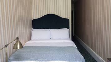 Una habitación de hotel con una cama, una lámpara de noche y papel tapiz a rayas.