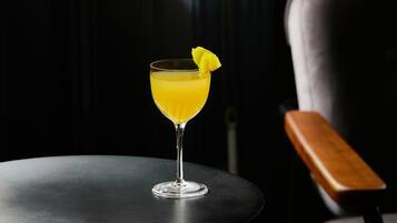 A cocktail on a small round table with a chair in the background.