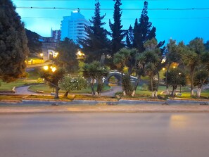 A landscaped area with a curved pathway, palm trees, and a bridge.