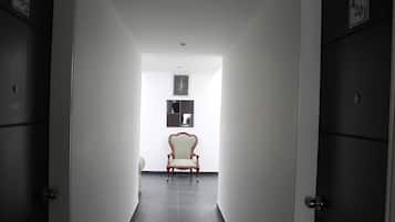 A hallway with a chair, doors, and a framed picture on the wall.
