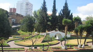 A landscaped garden with pathways, trees, and a white building.