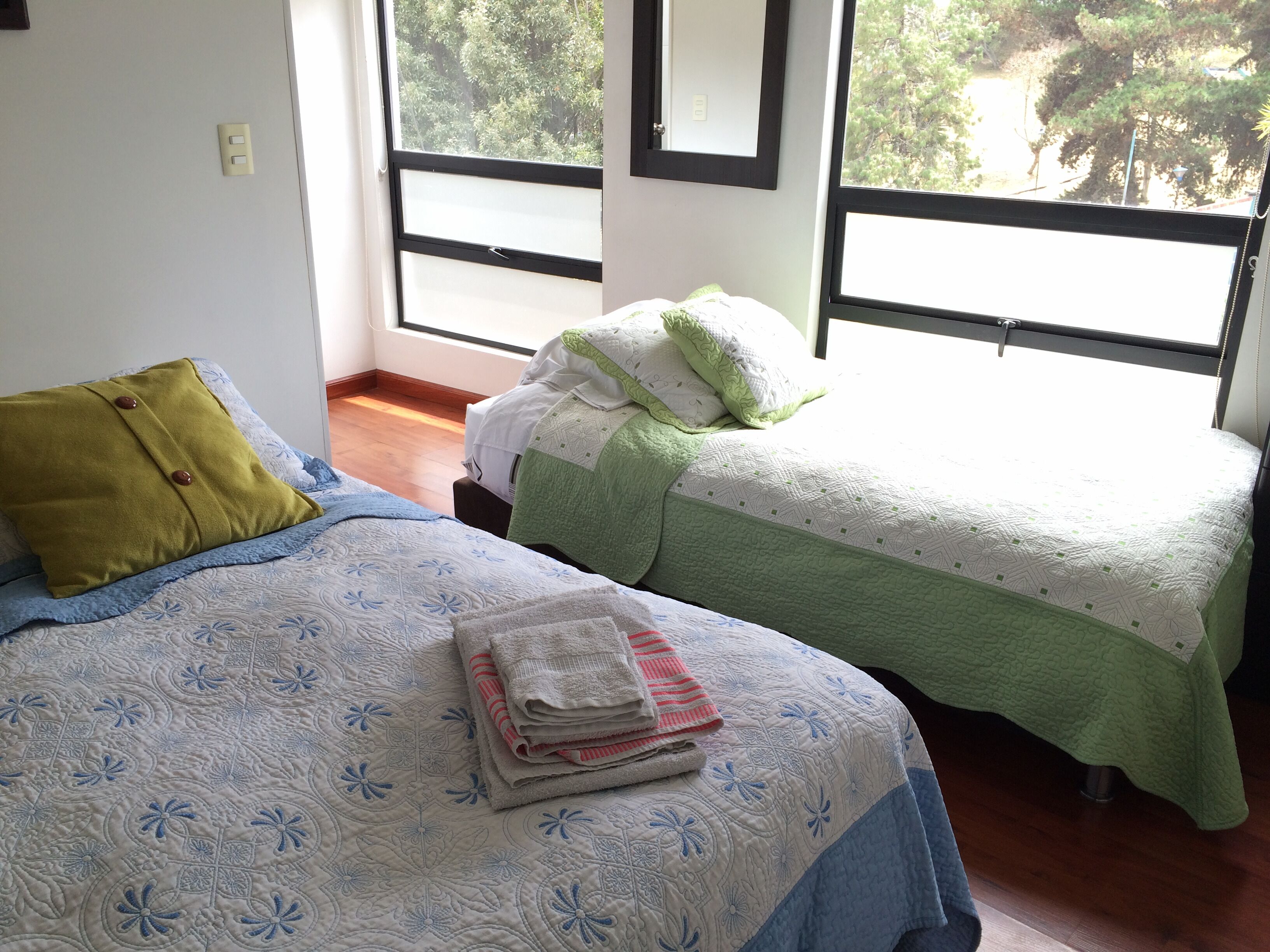 Une chambre avec deux lits, une fenêtre et un plancher en bois.