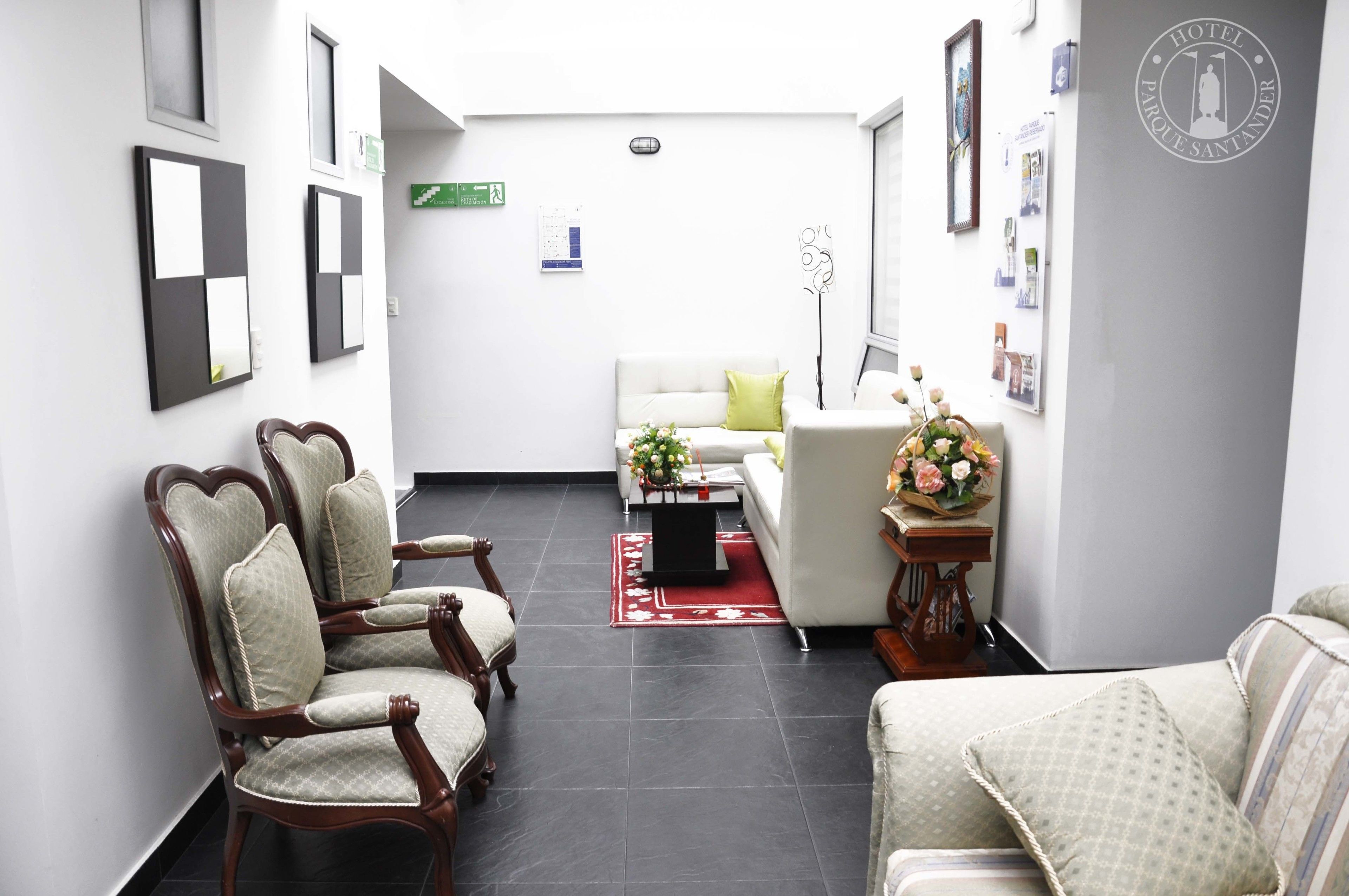 A hotel lobby with a reception desk, seating area, and a wall with framed pictures and a logo.