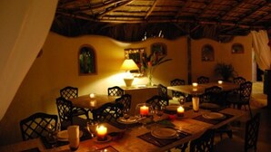 A dining area with a thatched roof, wooden tables, and chairs. - Hotel Coco Plaza (Las Terrenas)
