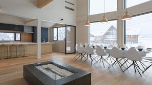 A modern kitchen with a dining area, wooden flooring, and large windows. - The Orchards Niseko (Kutchan)