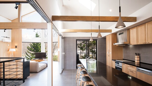 A modern kitchen with wooden cabinets, a stainless steel island, and bar stools. - The Orchards Niseko (Kutchan)