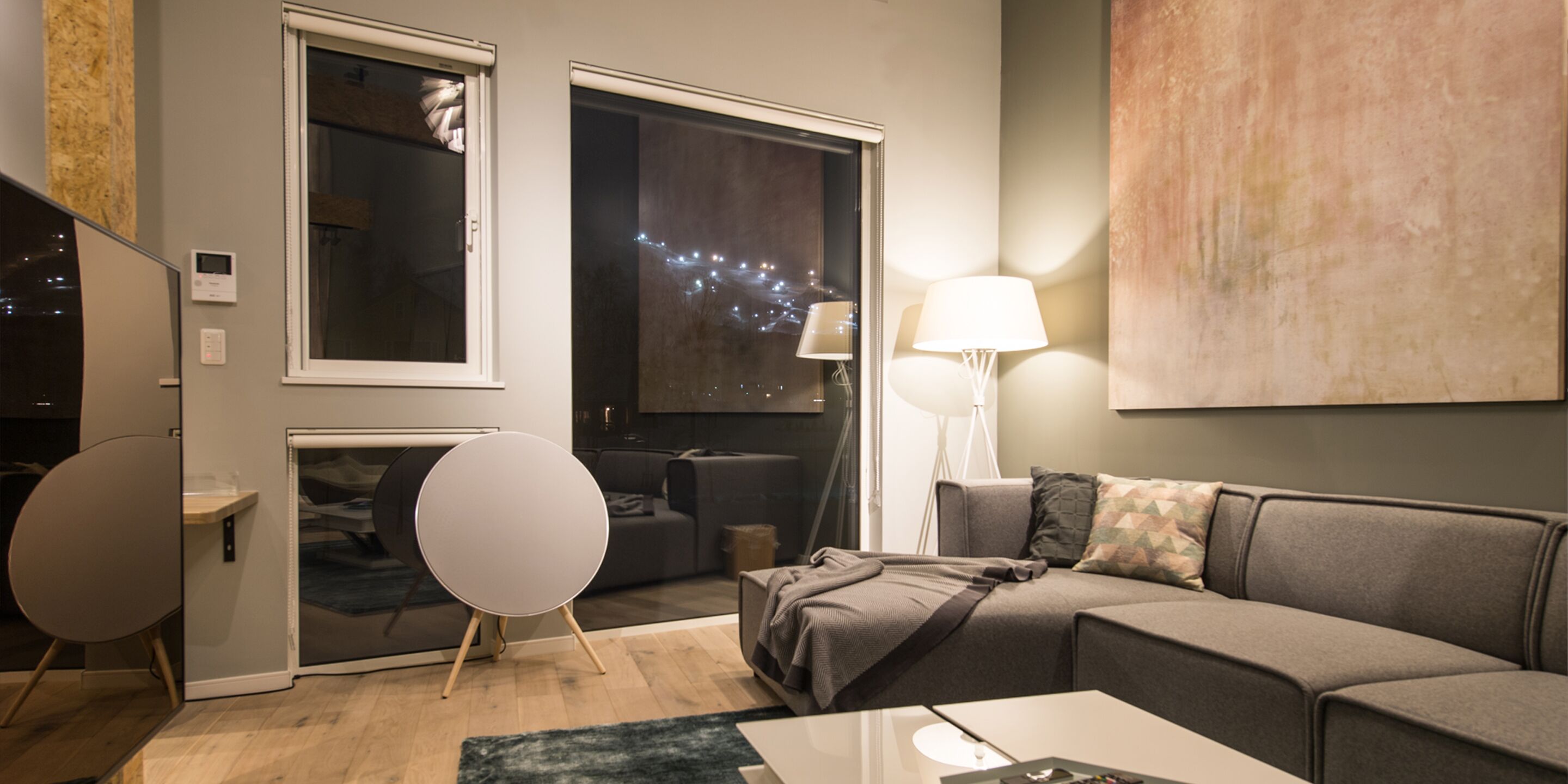 A modern living room with a grey sofa, a round table, and a lamp.