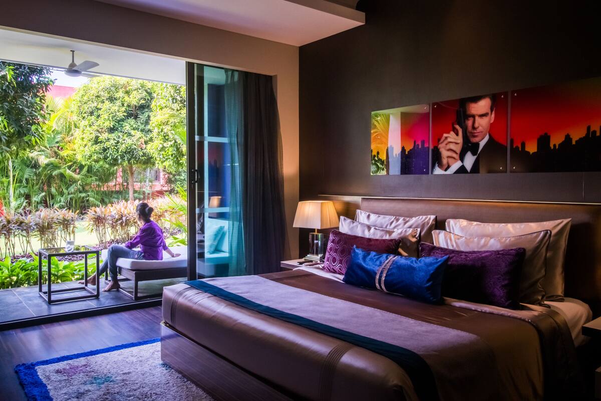 Un hotel moderno con una cama grande, vistas de un jardín a través de una puerta corrediza y un cuadro de la ciudad en la pared.