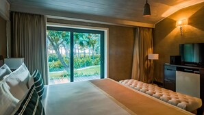 A hotel room with a large bed, a television, a desk, and a view of a tropical garden. - Planet Hollywood Goa Beach Resort (Utorda)