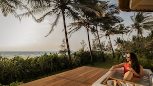 A woman in a hot tub with a tray of food and drinks, overlooking a beach with palm trees. - Planet Hollywood Goa Beach Resort (Utorda)