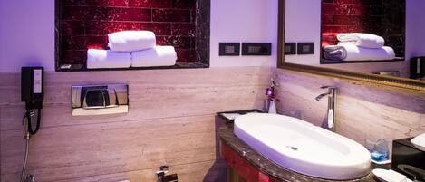 A modern bathroom with a white sink, a mirror, a heated towel rack, and a window with red-tinted glass.
