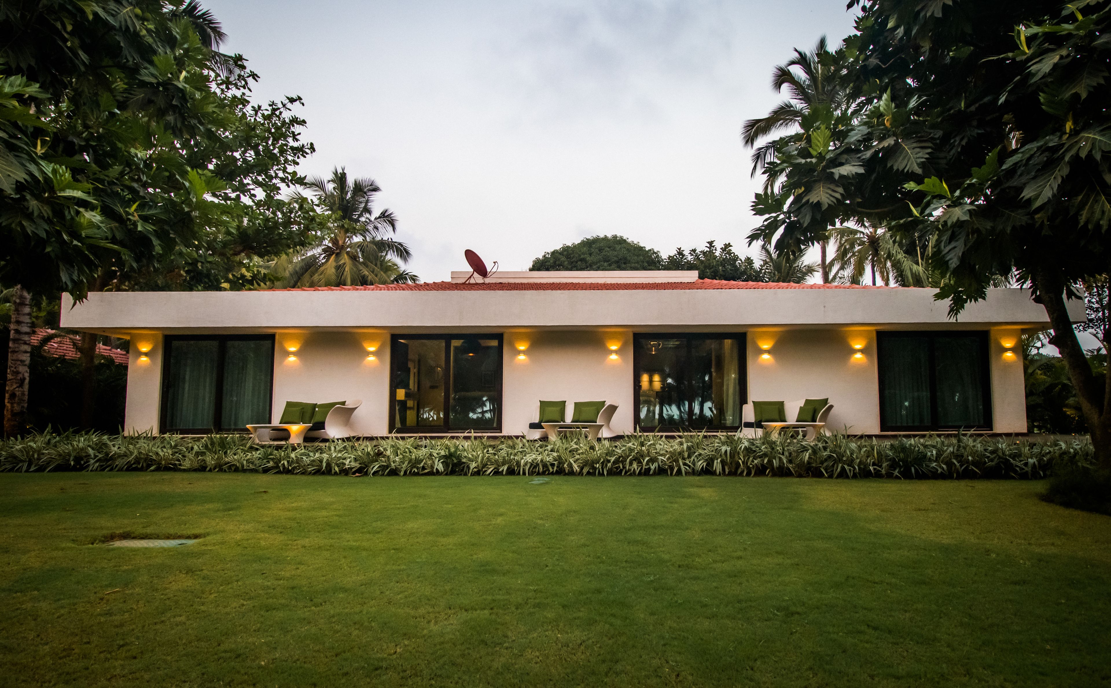 A modern house with a flat roof, large windows, and outdoor seating.