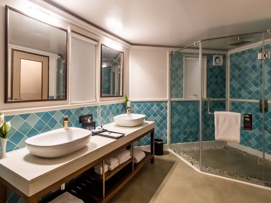 Un baño con dos lavamanos, un espejo y una cabina de ducha de vidrio.