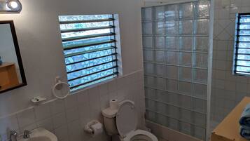 A bathroom with a toilet, sink, and a window with bars.