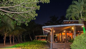 Un edificio frente a la playa con un área de asientos al aire libre techada y un bar.