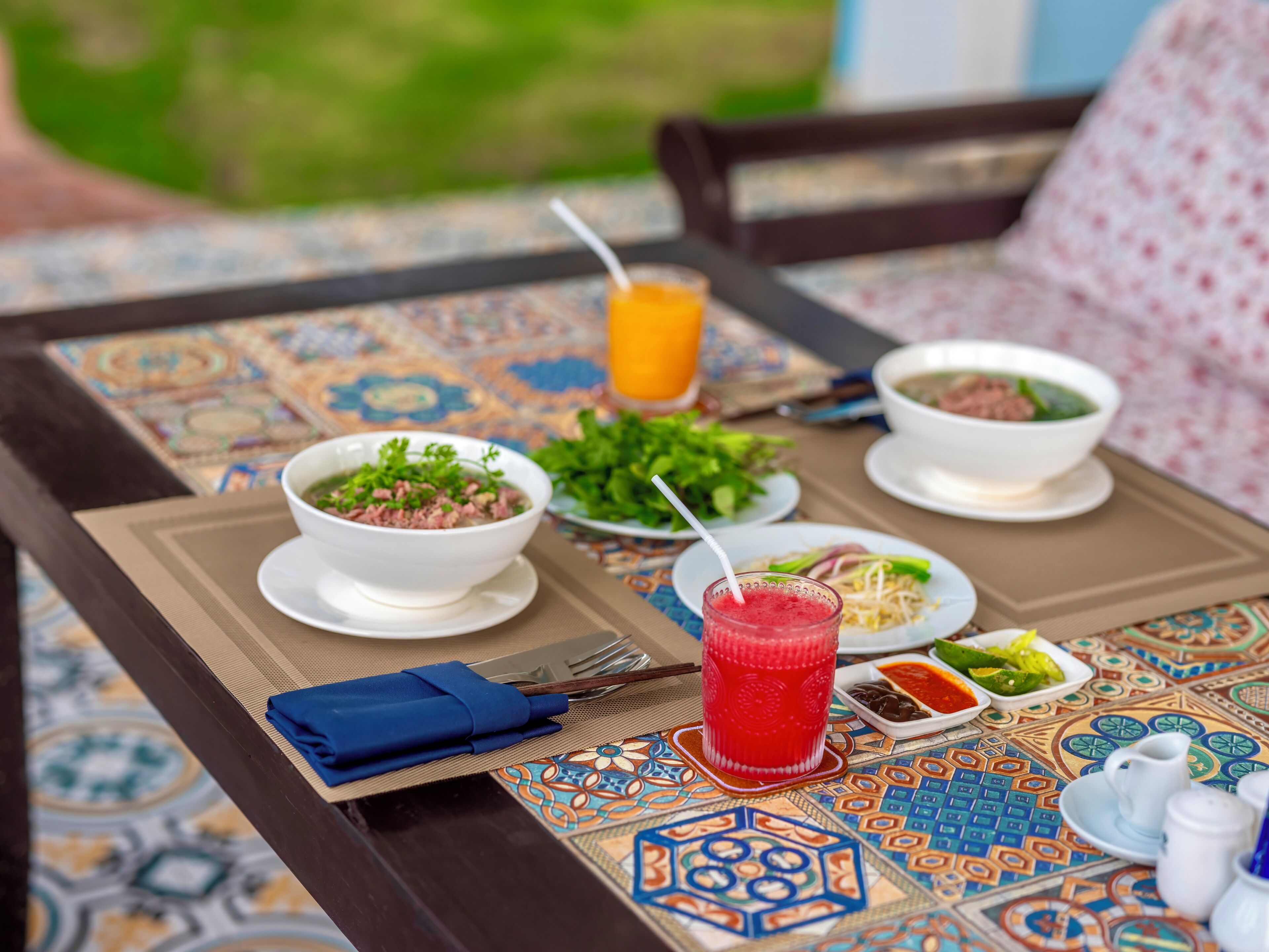 A table set with bowls of soup, a salad, and a drink, with a napkin and utensils.
