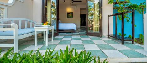 Une chambre d’hôtel avec un lit, une petite table sur laquelle se trouvent des fruits, et une vue sur le jardin.
