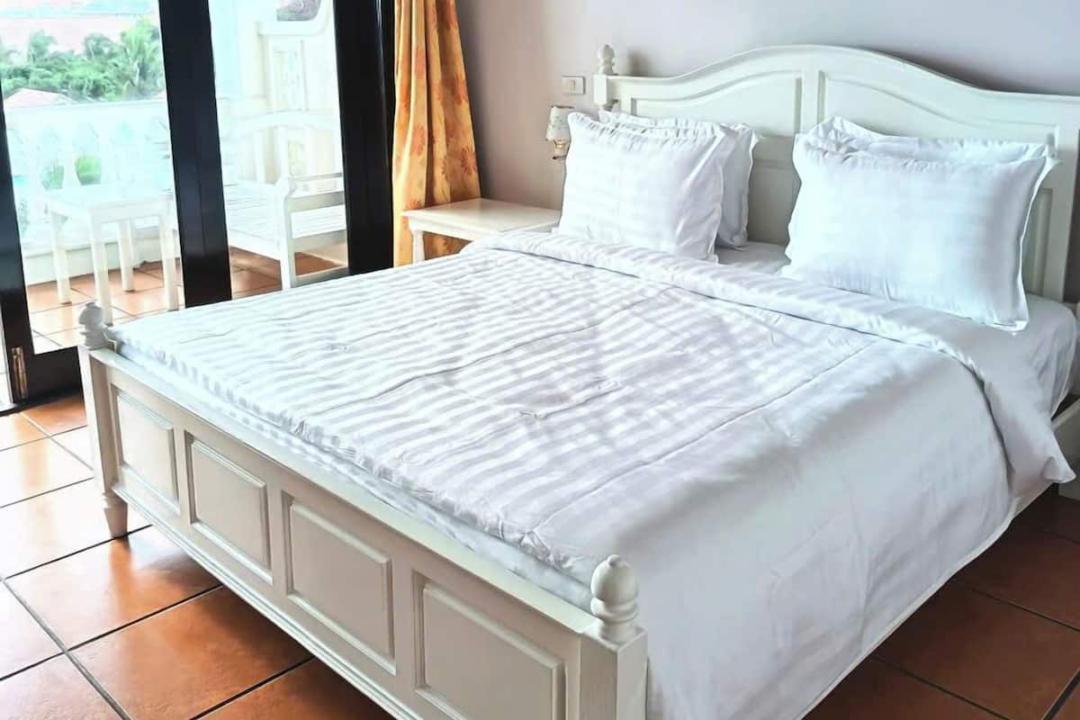 Ruime slaapkamer met een groot bed, nachtkastje en uitzicht op de omgeving door een schuifdeur.