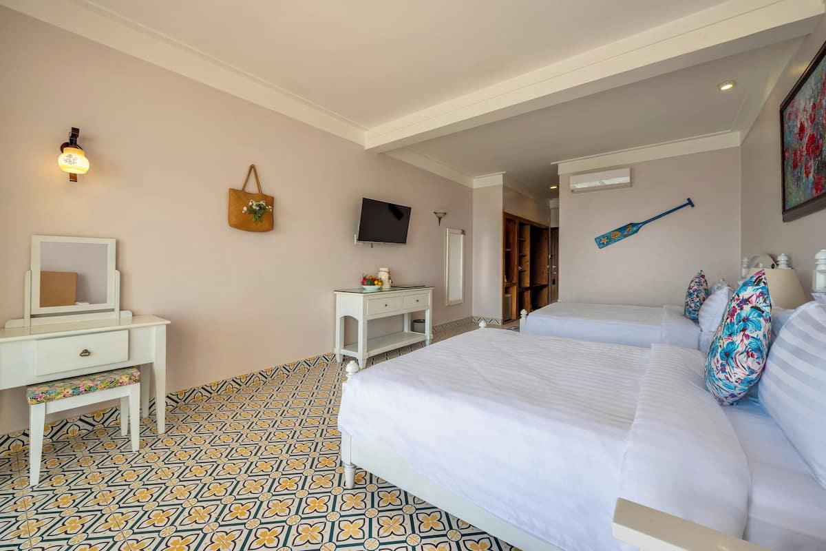 Een hotelkamer met twee bedden, een bureau, een kaptafel en een televisie.