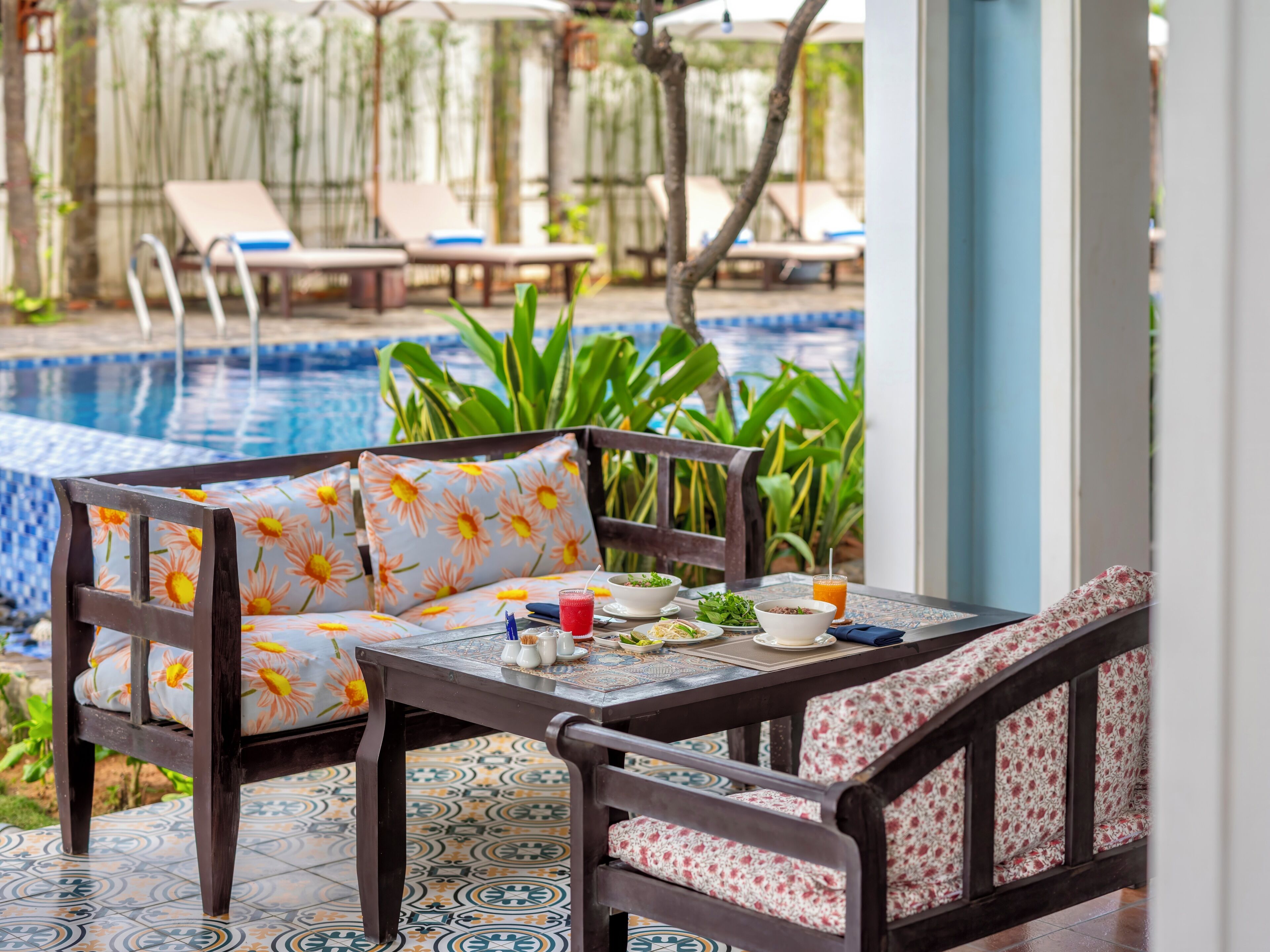 A poolside seating area with a table, chairs, and a view of the pool.