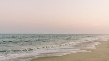 Vlak bij het strand, wit zand, ligstoelen, parasols