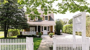 A two-story house with a front porch, a white picket fence, and a sign that reads "The Roundtree."