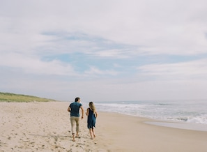 Perto da praia, areia branca, espreguiçadeiras, guarda-sóis 
