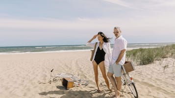 Vlak bij het strand, wit zand, ligstoelen aan het strand, parasols