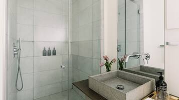 A modern bathroom with a glass-enclosed shower, a granite sink, and a large mirror.