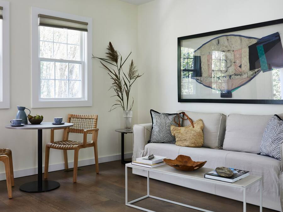 Una sala de estar moderna con un sofá blanco, una mesa de centro y un comedor con mesa y sillas.