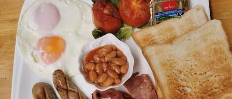 A breakfast plate with eggs, sausages, bacon, toast, tomatoes, and beans.