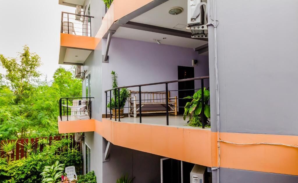 A multi-story building with balconies, outdoor seating, and greenery.