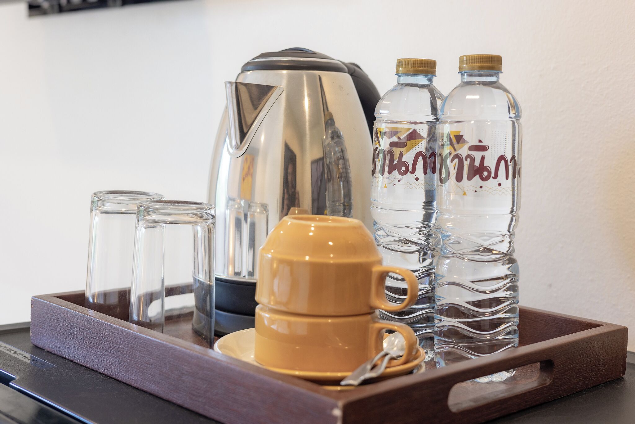 Ein Tablett mit einer Kaffeemaschine, zwei Gläsern, einer gelben Tasse und zwei Wasserflaschen.