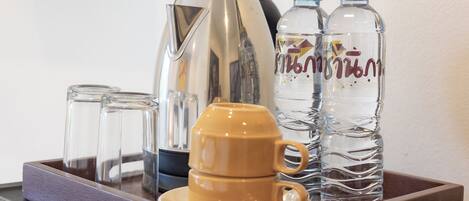 Ein Tablett mit einer Kaffeemaschine, zwei Gläsern, einer gelben Tasse und zwei Wasserflaschen.