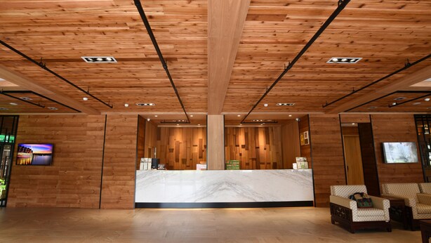 A reception area with a wooden ceiling, marble reception desk, and a seating area with patterned sofas. - Cilan Resort (Datong)