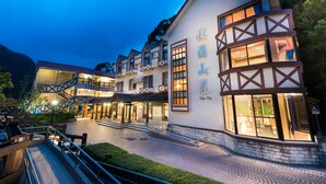 A multi-story hotel with a traditional architectural style, featuring a prominent entrance and a well-lit outdoor area. - Cilan Resort (Datong)