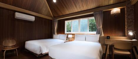 Habitación de hotel con dos camas, un escritorio, una silla y un ventanal con cortinas.