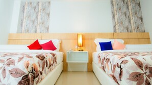 A hotel room with two beds, each with a floral bedspread, a nightstand with a lamp, and wooden headboards. - The Rama Residence Chiang Rai (Chiang Rai)
