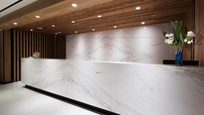 A reception desk with a marble top, wooden paneling, and recessed lighting. - Mingchih Resort (Datong)