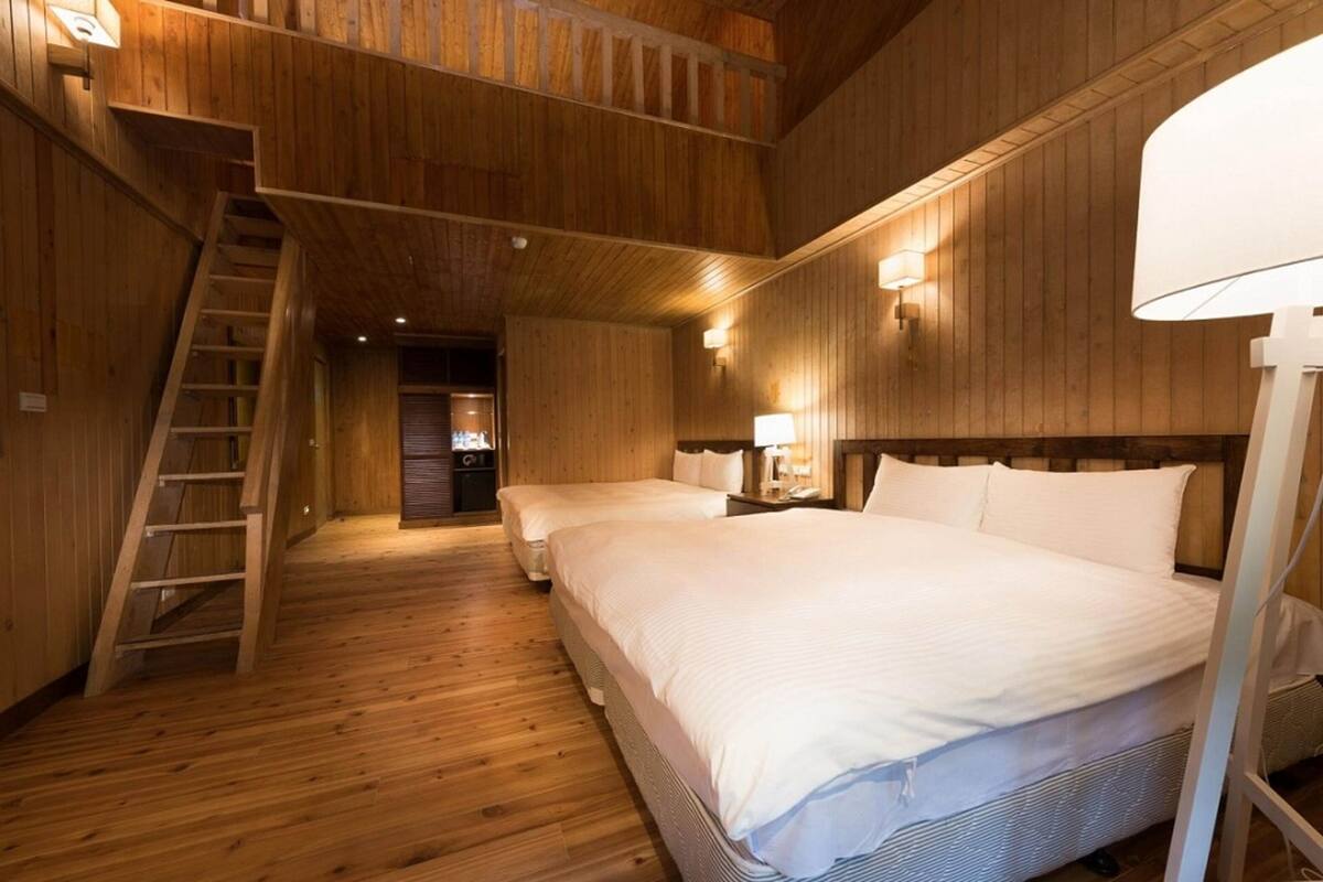 Ein holzgetäfeltes Zimmer im Blockhausstil mit zwei Betten, einer Treppe und Wandlampen.